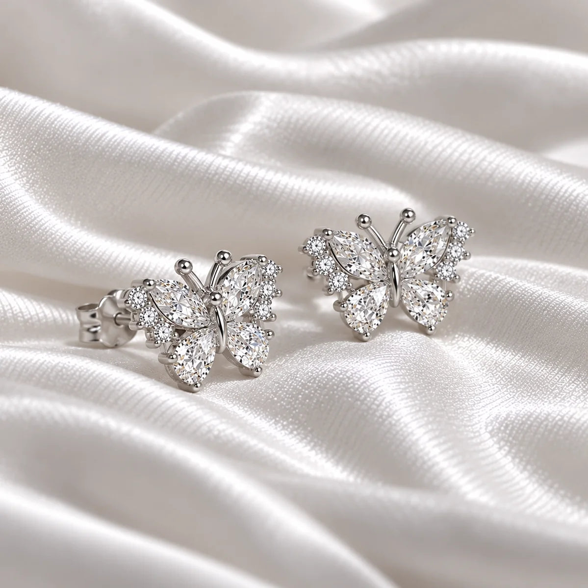 Diamond_butterfly_earrings_in_sterling_silver_with_lab_grown_diamonds_at_side_angle_view_on_soft_fabric_background