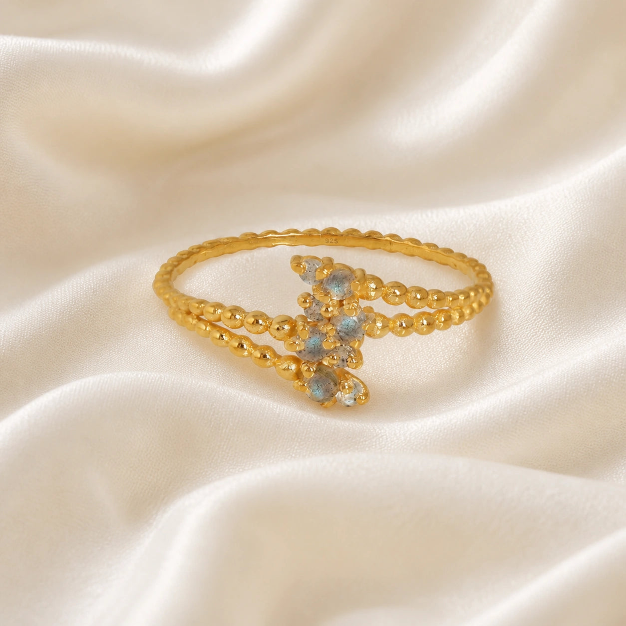 Spiral_ring_with_gold_plated_silver_bubble_band_and_labradorite_stones_at_front_angle_view_on_soft_fabric_background
