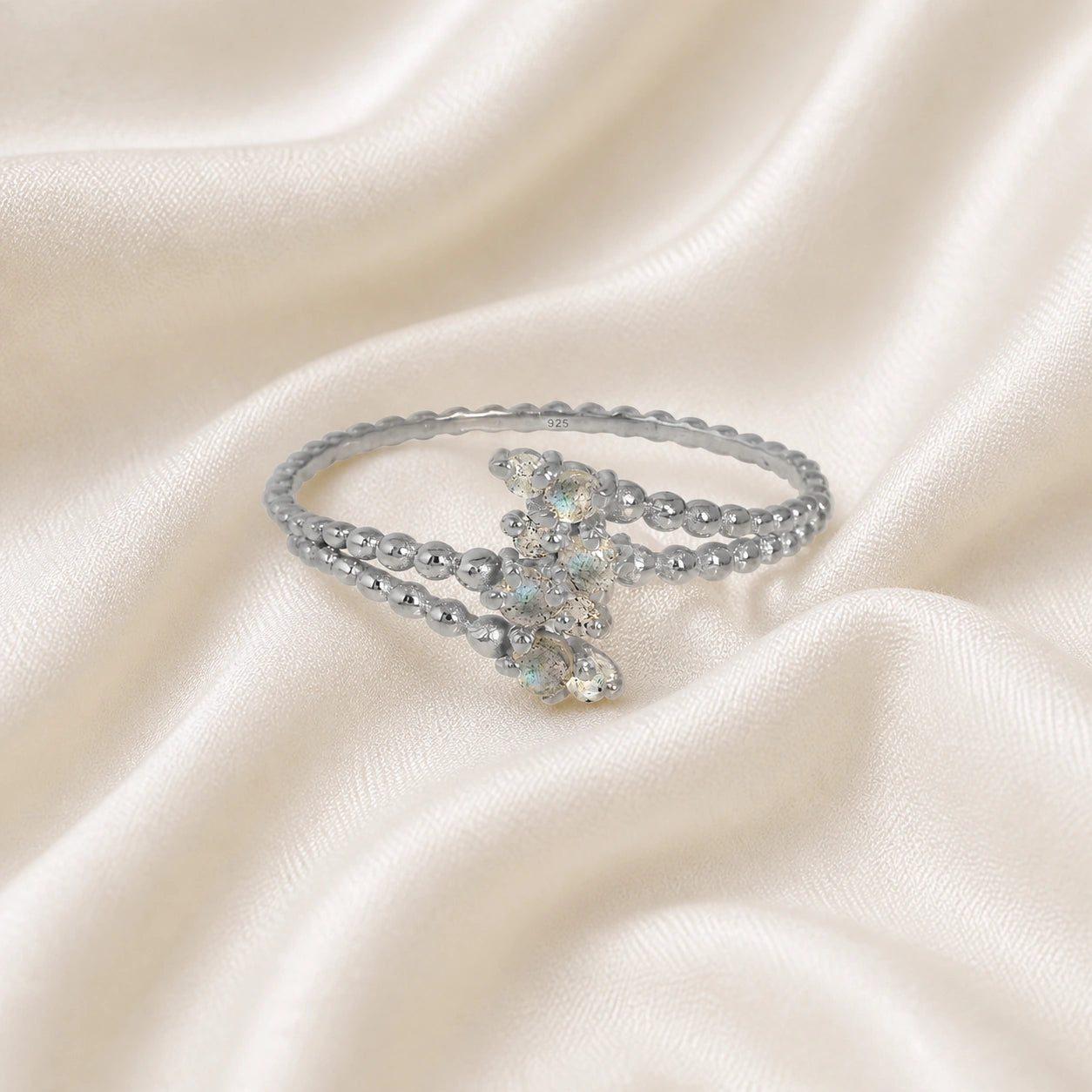 Spiral_ring_with_sterling_silver_bubble_band_and_labradorite_stones_at_front_angle_view_on_soft_fabric_background