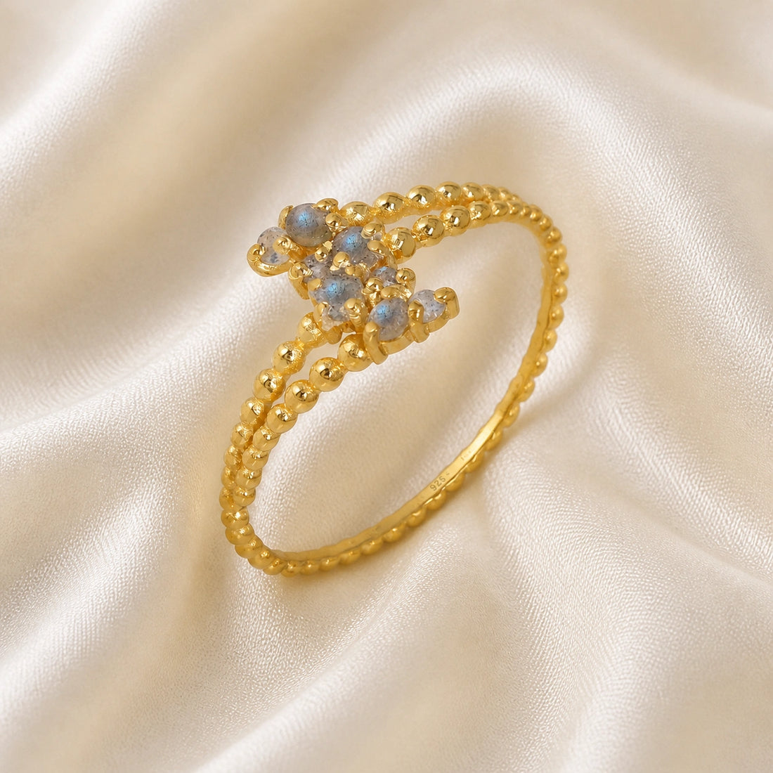 Spiral_ring_with_gold_plated_silver_bubble_band_and_labradorite_stones_at_side_angle_view_on_soft_fabric_background