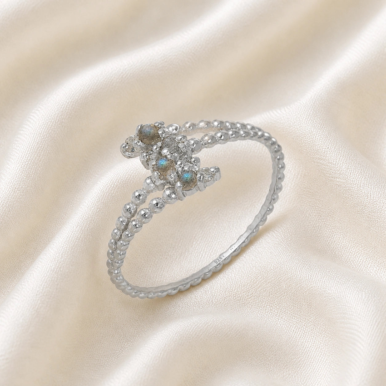 Spiral_ring_with_sterling_silver_bubble_band_and_labradorite_stones_at_side_angle_view_on_soft_fabric_background