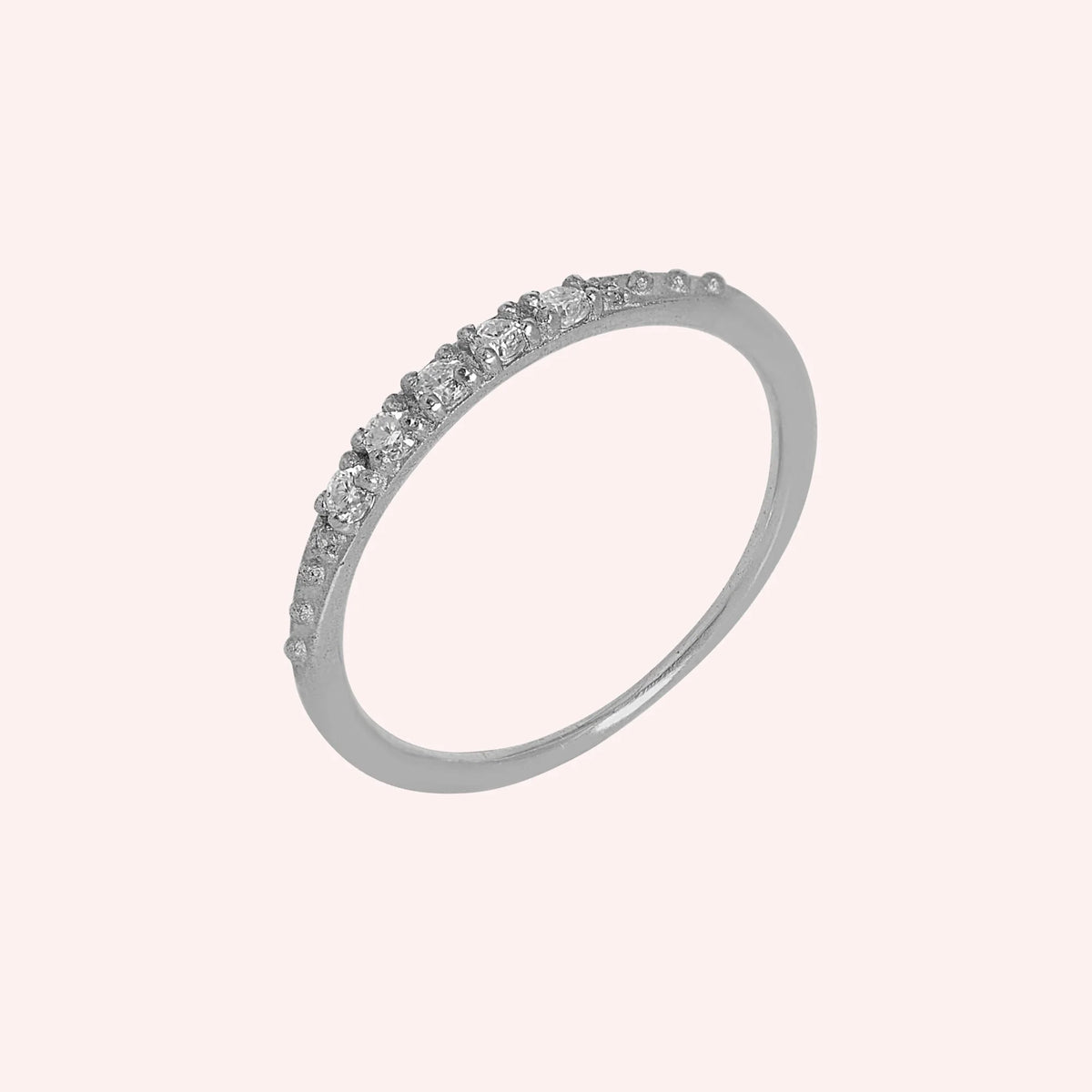 Stackable_ring_in_sterling_silver_with_CZ_stones_at_side_angle_view_on_solid_pink_background