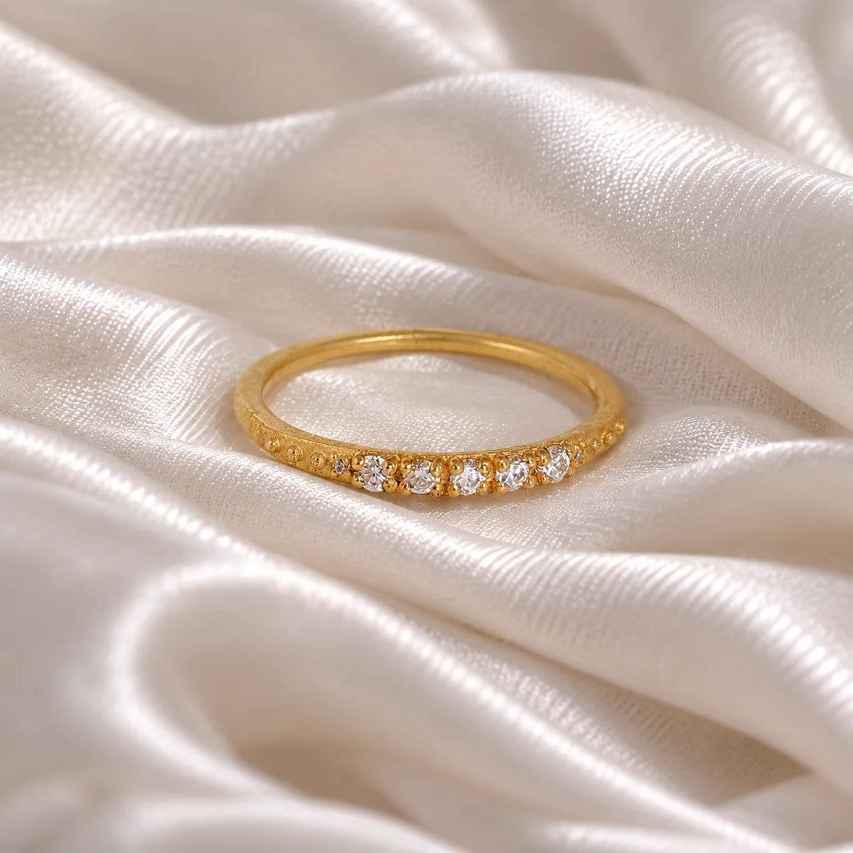 Stackable_ring_in_gold_plated_silver_with_CZ_stones_at_front_angle_view_on_soft_fabric_background