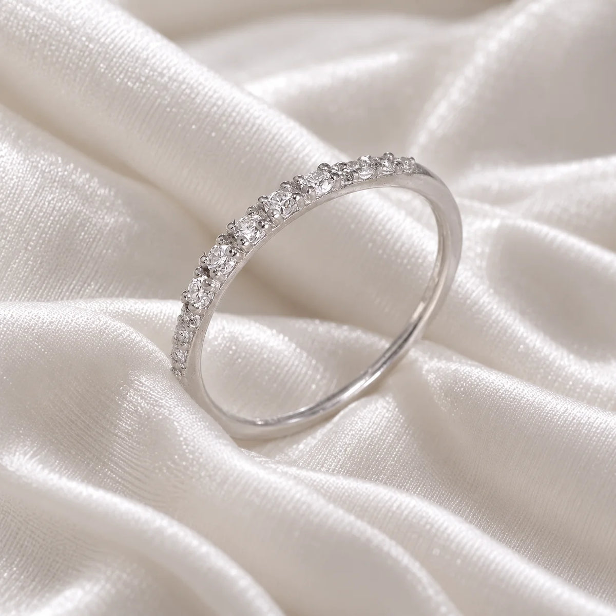 Stackable_ring_in_sterling_silver_with_CZ_stones_at_side_angle_view_on_soft_fabric_background