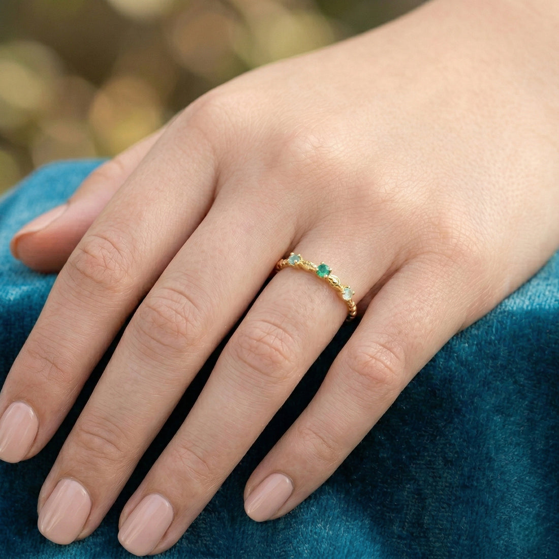 Stackable-ring-with-green-gemstones-gold-plated-silver-angled-view-on-white-satin-background