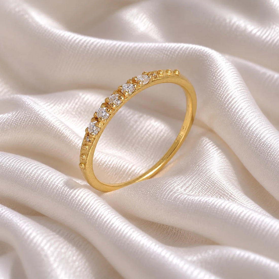 Stackable_ring_in_gold_plated_silver_with_CZ_stones_at_side_angle_view_on_soft_fabric_background