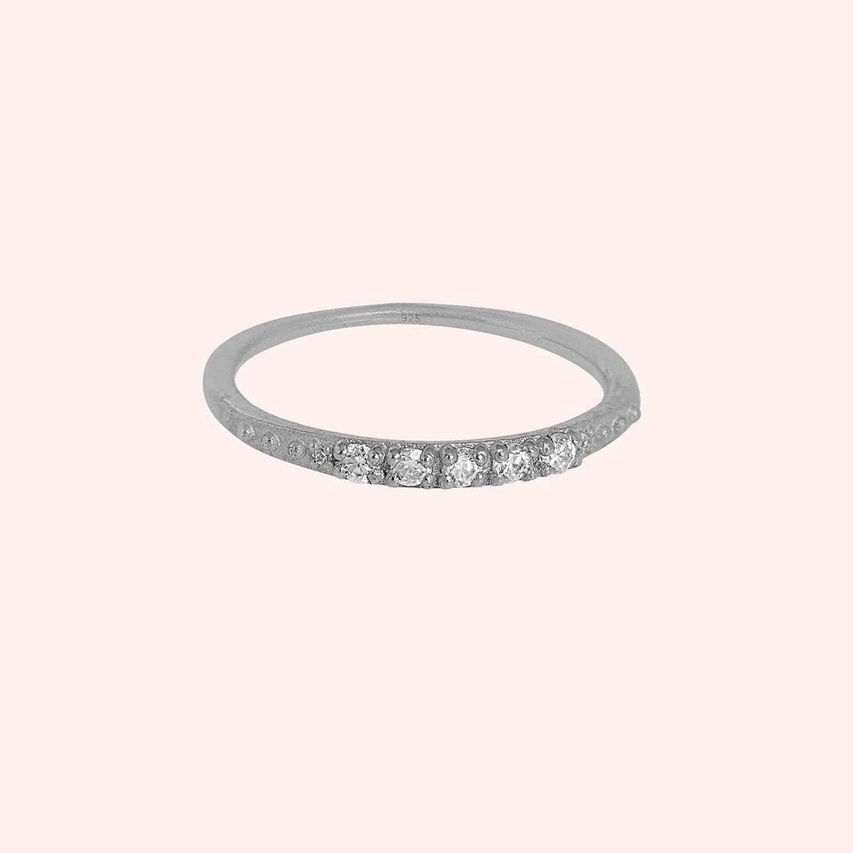 Stackable_ring_in_sterling_silver_with_CZ_stones_at_front_angle_view_on_solid_pink_background