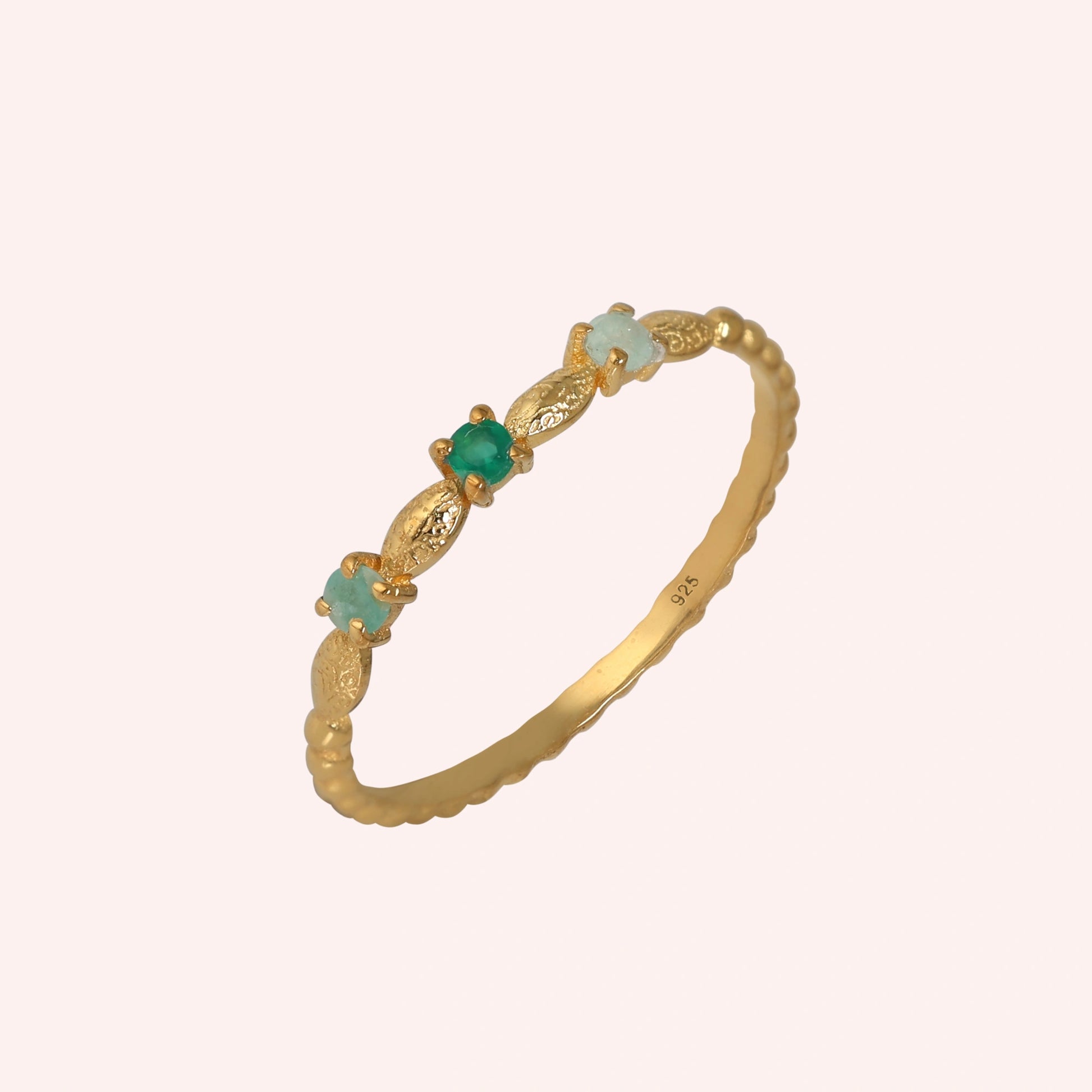 Stackable-ring-with-green-gemstones-gold-plated-silver-angled-view-on-soft-pink-background