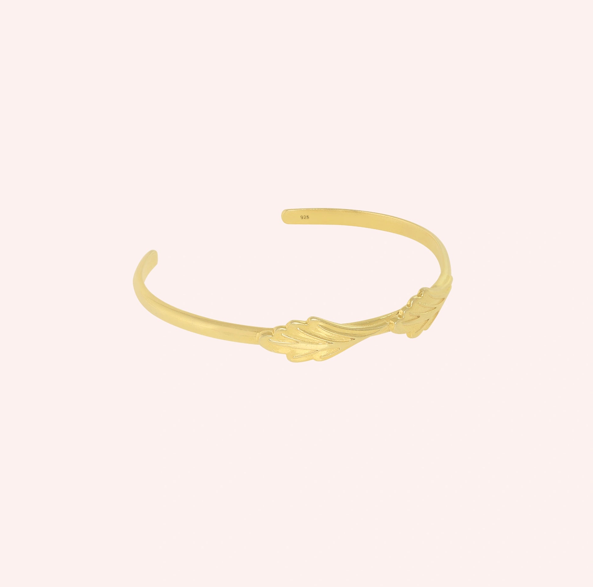 Stacking_bracelet_in_gold_plated_silver_with_a_leaf_design_band_at_slight_angle_view_on_solid_pink_background