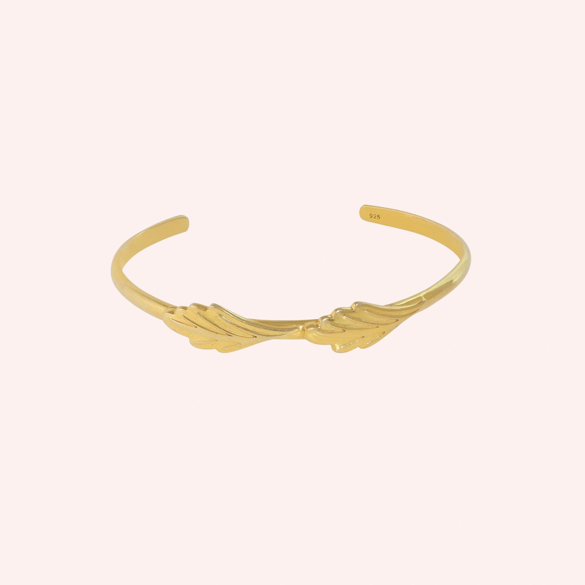 Stacking_bracelet_in_gold_plated_silver_with_a_leaf_design_band_at_front_angle_view_on_solid_pink_background