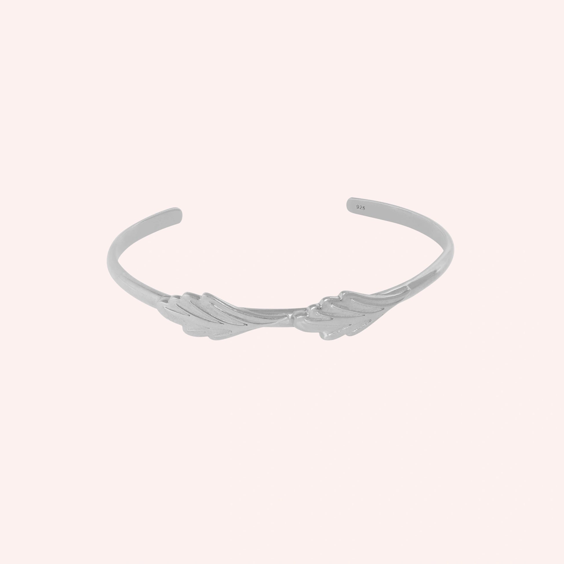 Stacking_bracelet_in_sterling_silver_with_a_leaf_design_band_at_front_angle_view_on_solid_pink_background