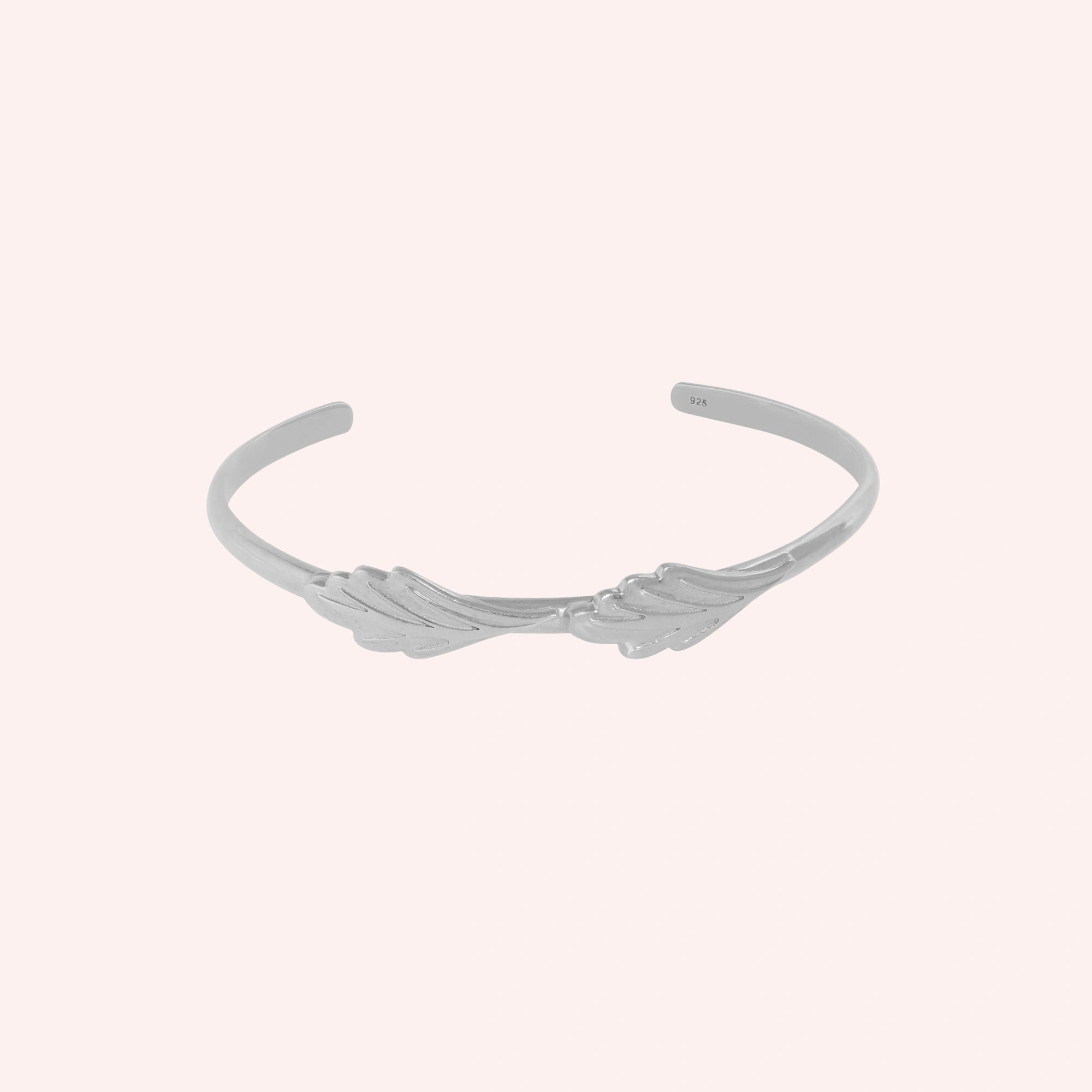 Stacking_bracelet_in_sterling_silver_with_a_leaf_design_band_at_front_angle_view_on_solid_pink_background