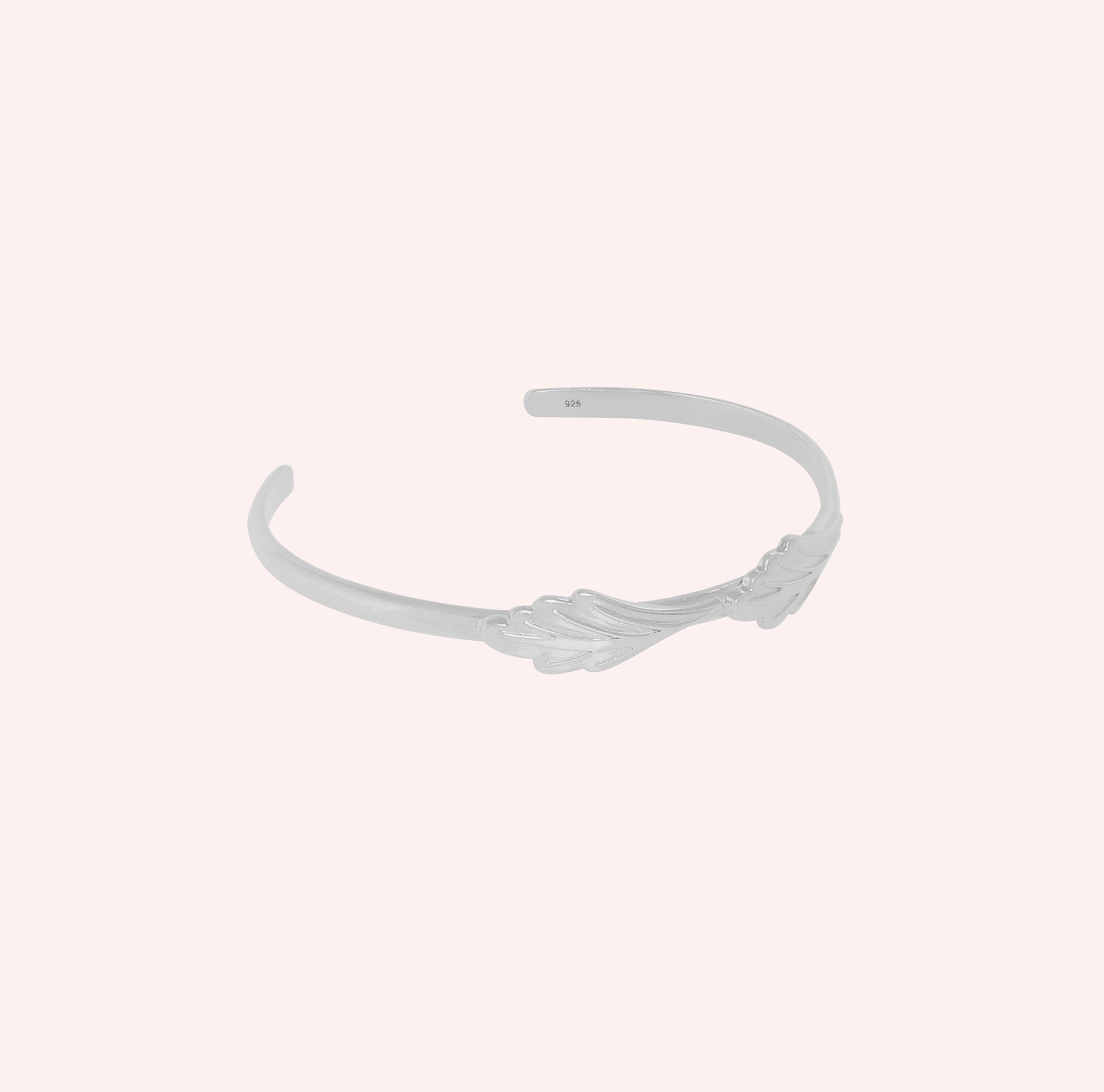 Stacking_bracelet_in_sterling_silver_with_a_leaf_design_band_at_slight_angle_view_on_solid_pink_background
