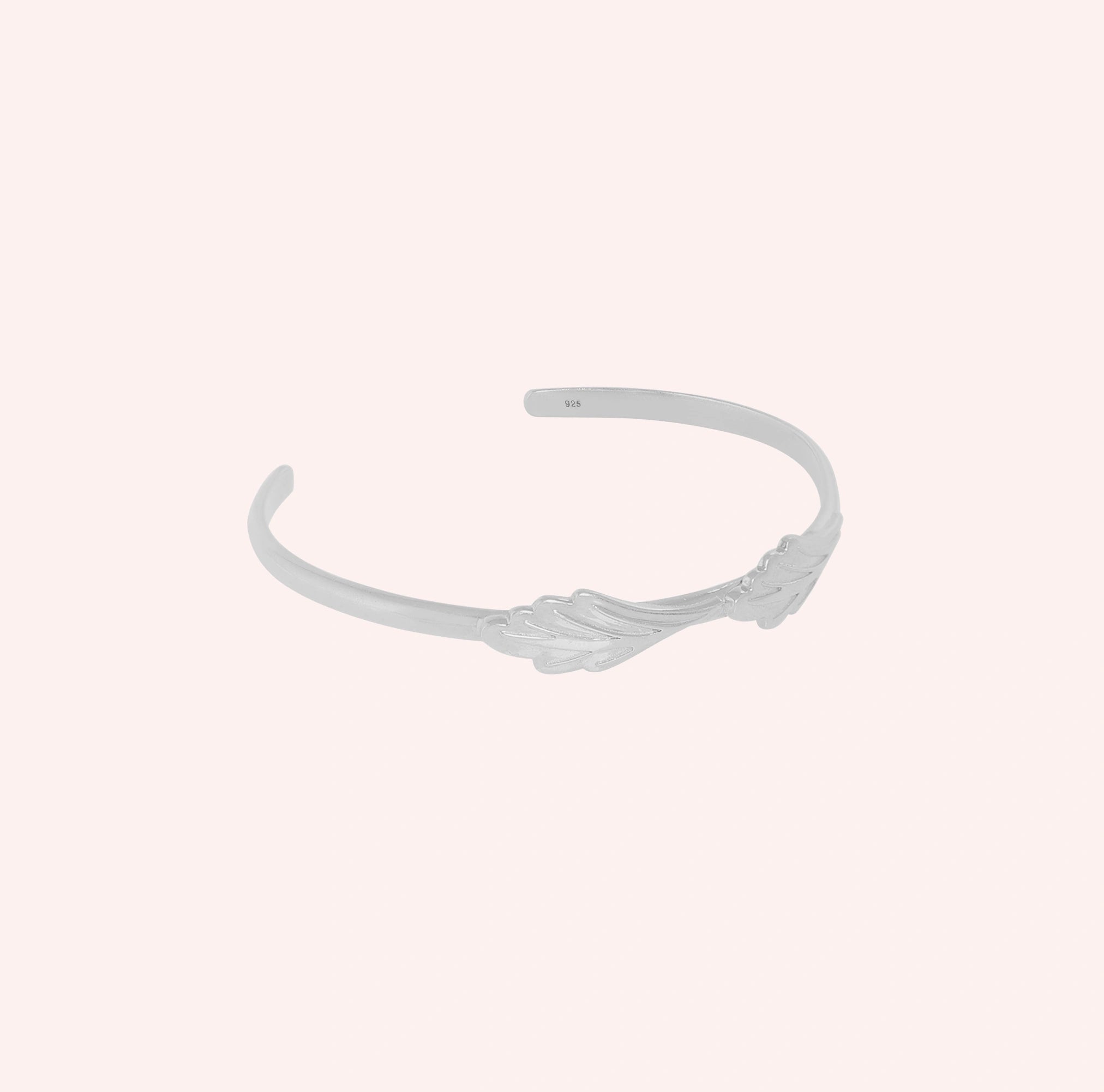 Stacking_bracelet_in_sterling_silver_with_a_leaf_design_band_at_slight_angle_view_on_solid_pink_background
