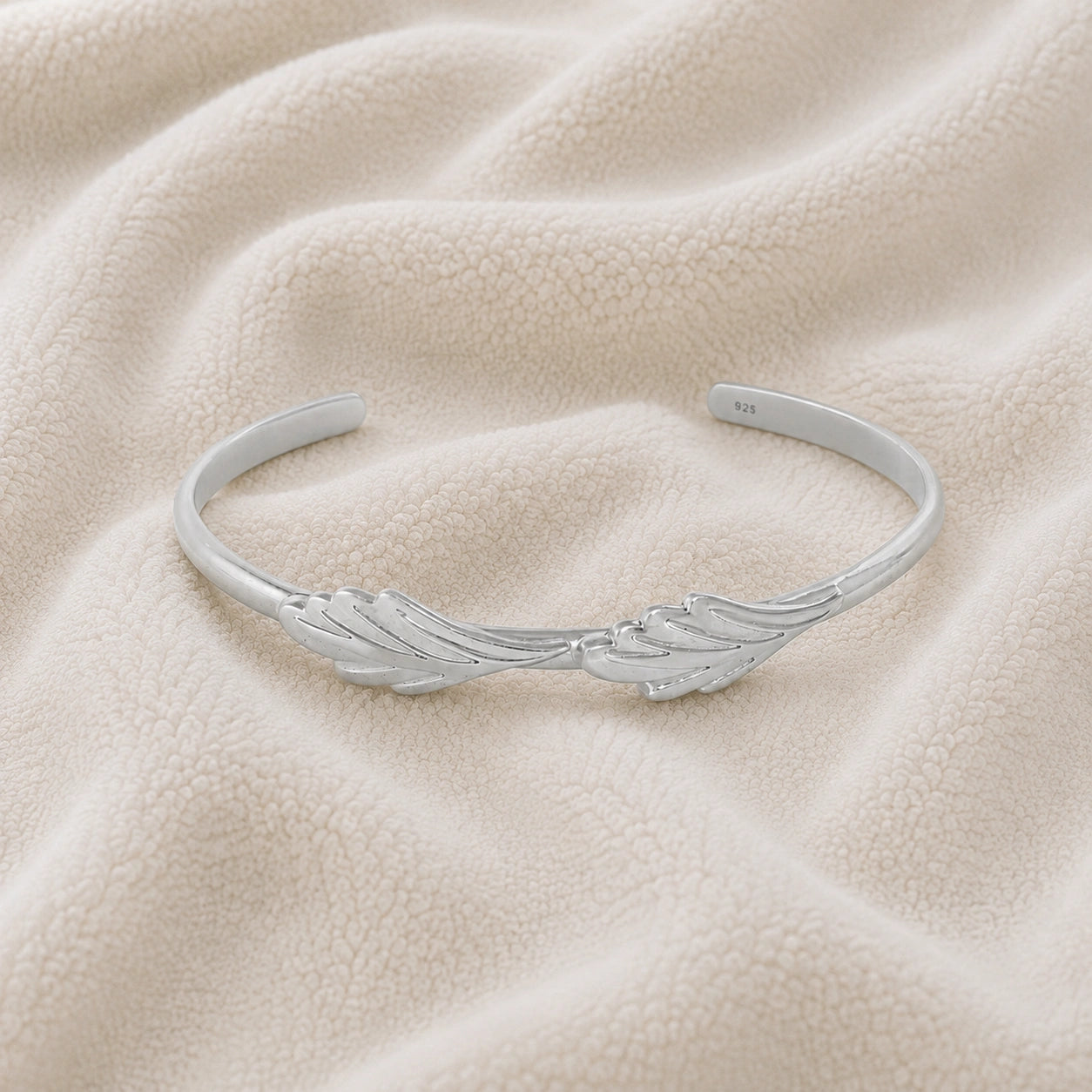 Stacking_bracelet_in_sterling_silver_with_a_leaf_design_band_at_front_angle_view_on_soft_fabric_background