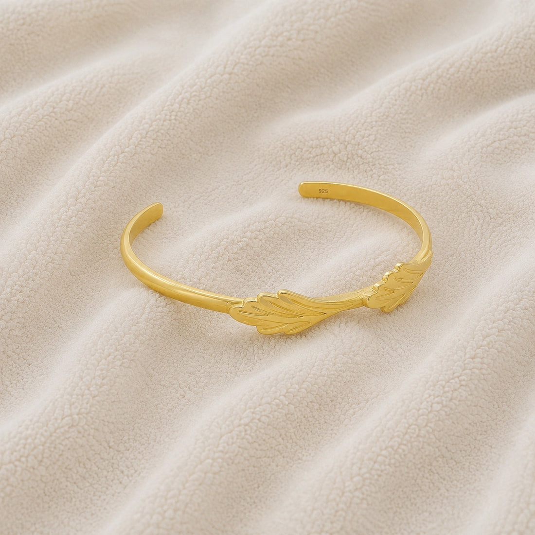 Stacking_bracelet_in_gold_plated_silver_with_a_leaf_design_band_at_slight_angle_view_on_soft_fabric_background