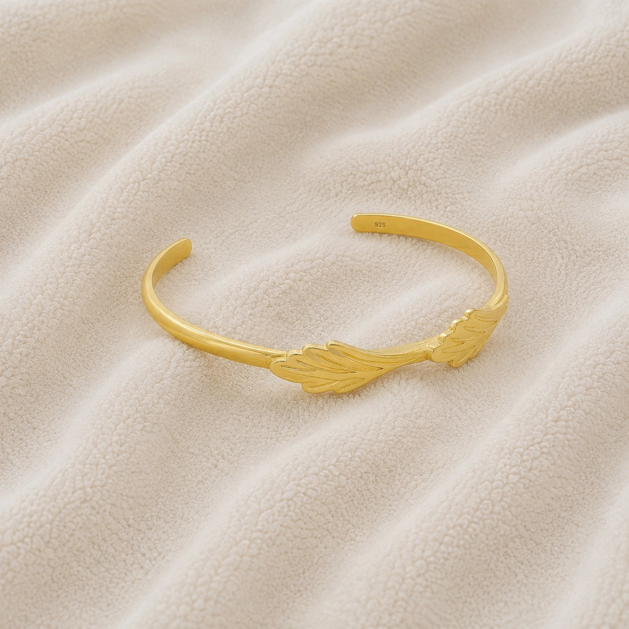 Stacking_bracelet_in_gold_plated_silver_with_a_leaf_design_band_at_slight_angle_view_on_soft_fabric_background