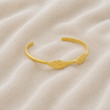 Stacking_bracelet_in_gold_plated_silver_with_a_leaf_design_band_at_slight_angle_view_on_soft_fabric_background