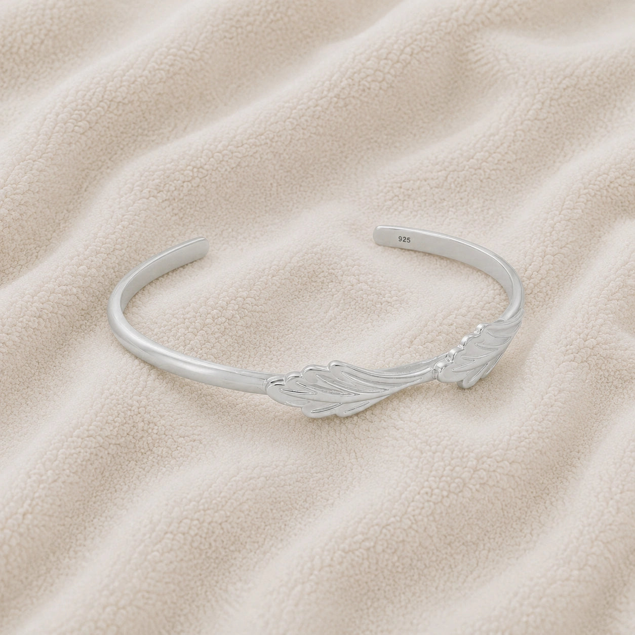 Stacking_bracelet_in_sterling_silver_with_a_leaf_design_band_at_slight_angle_view_on_soft_fabric_background