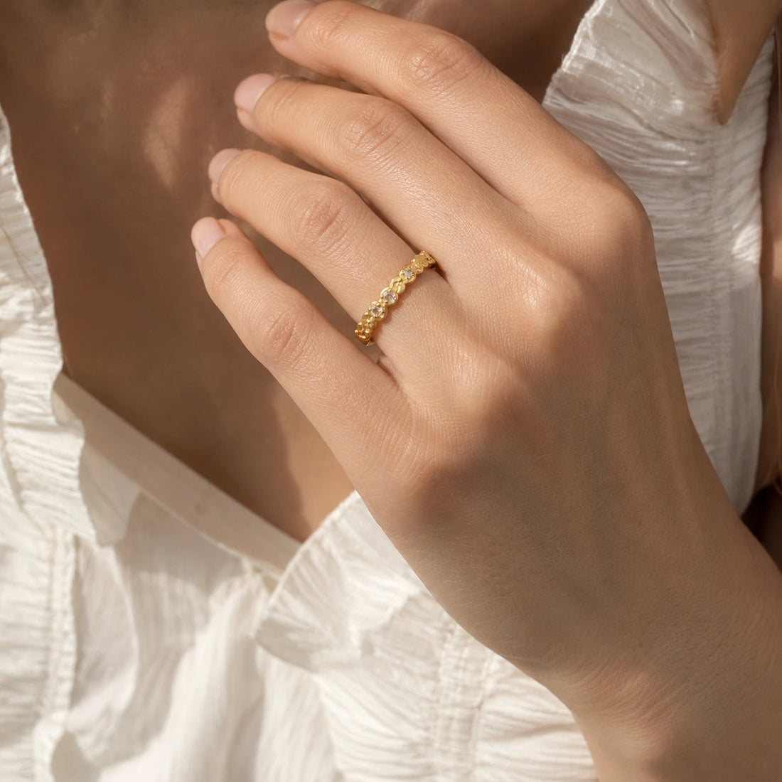 Stacking_ring_in_gold_plated_silver_textured_band_with_moonstones_in_angled_view_on_soft_fabric_background