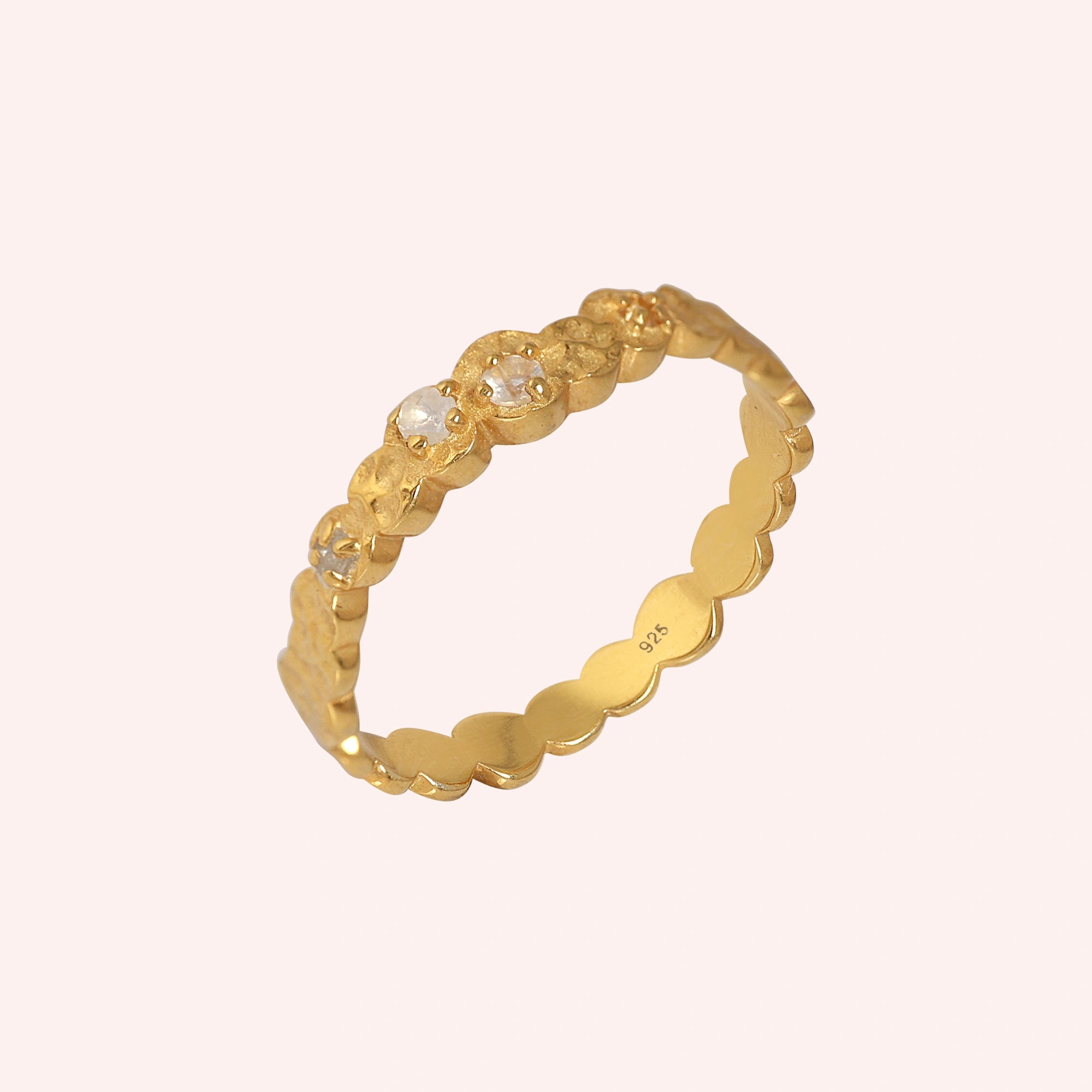 Stacking_ring_in_gold_plated_silver_textured_band_with_moonstones_in_angled_view_on_solid_pink_background