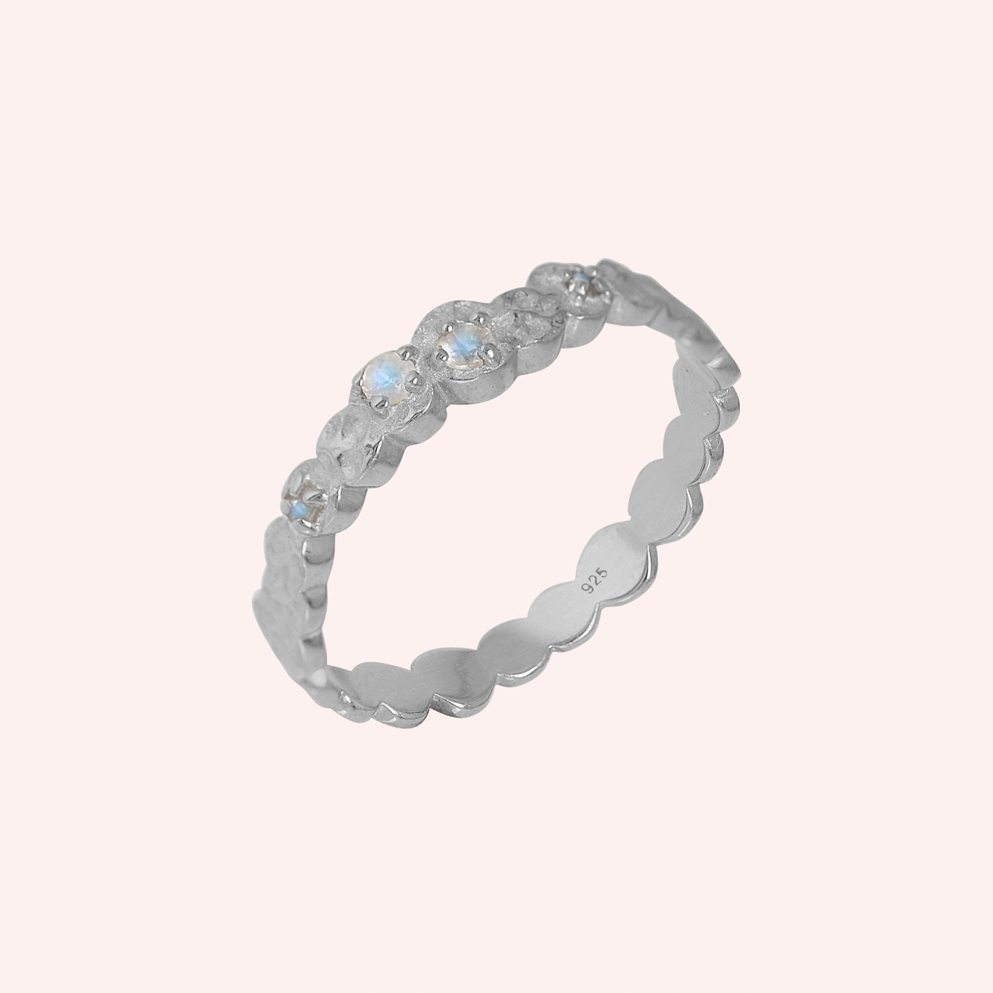 Stacking_ring_in_sterlingk_silver_textured_band_with_moonstones_in_angled_view_on_solid_pink_background