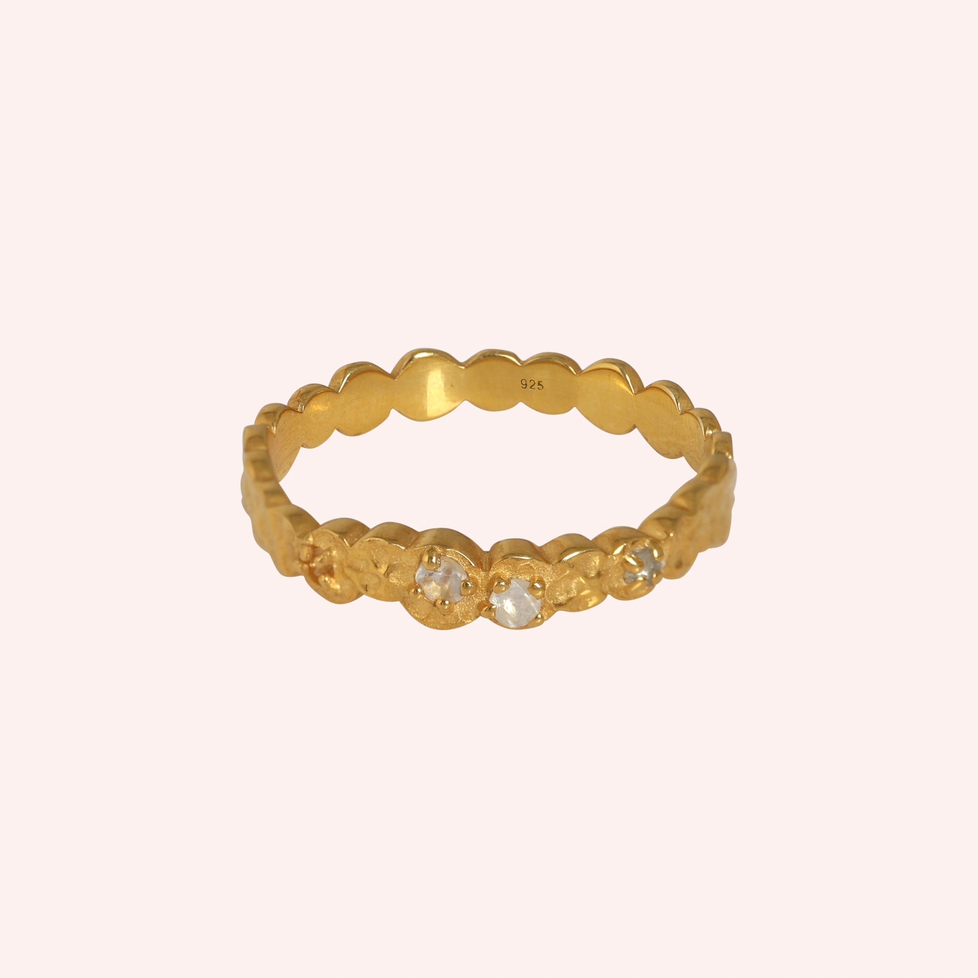 Stacking_ring_in_gold_plated_silver_textured_band_with_moonstones_in_front_angled_view_on_solid_pink_background