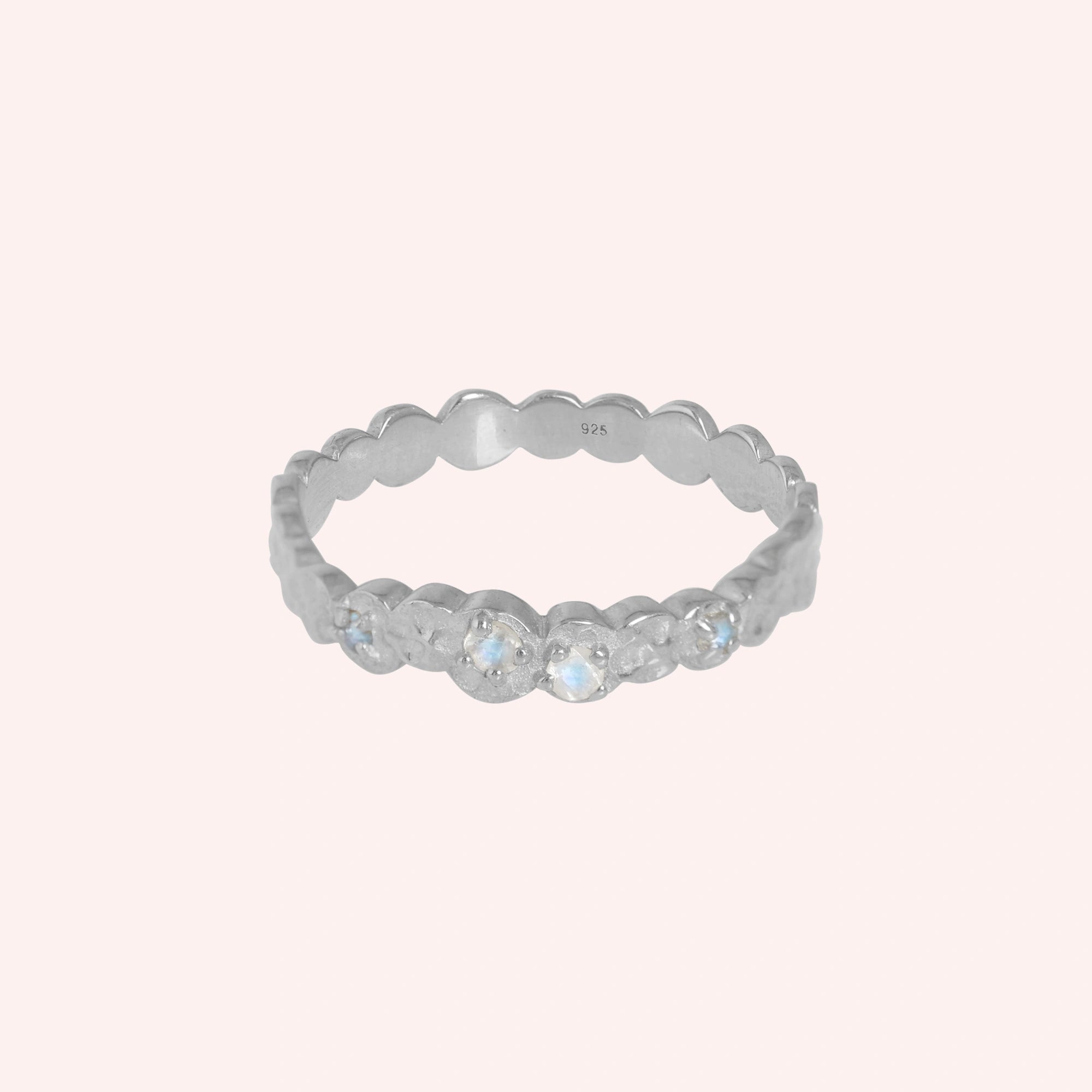 Stacking_ring_in_sterling_silver_textured_band_with_moonstones_in_front_angled_view_on_solid_backgroundpink