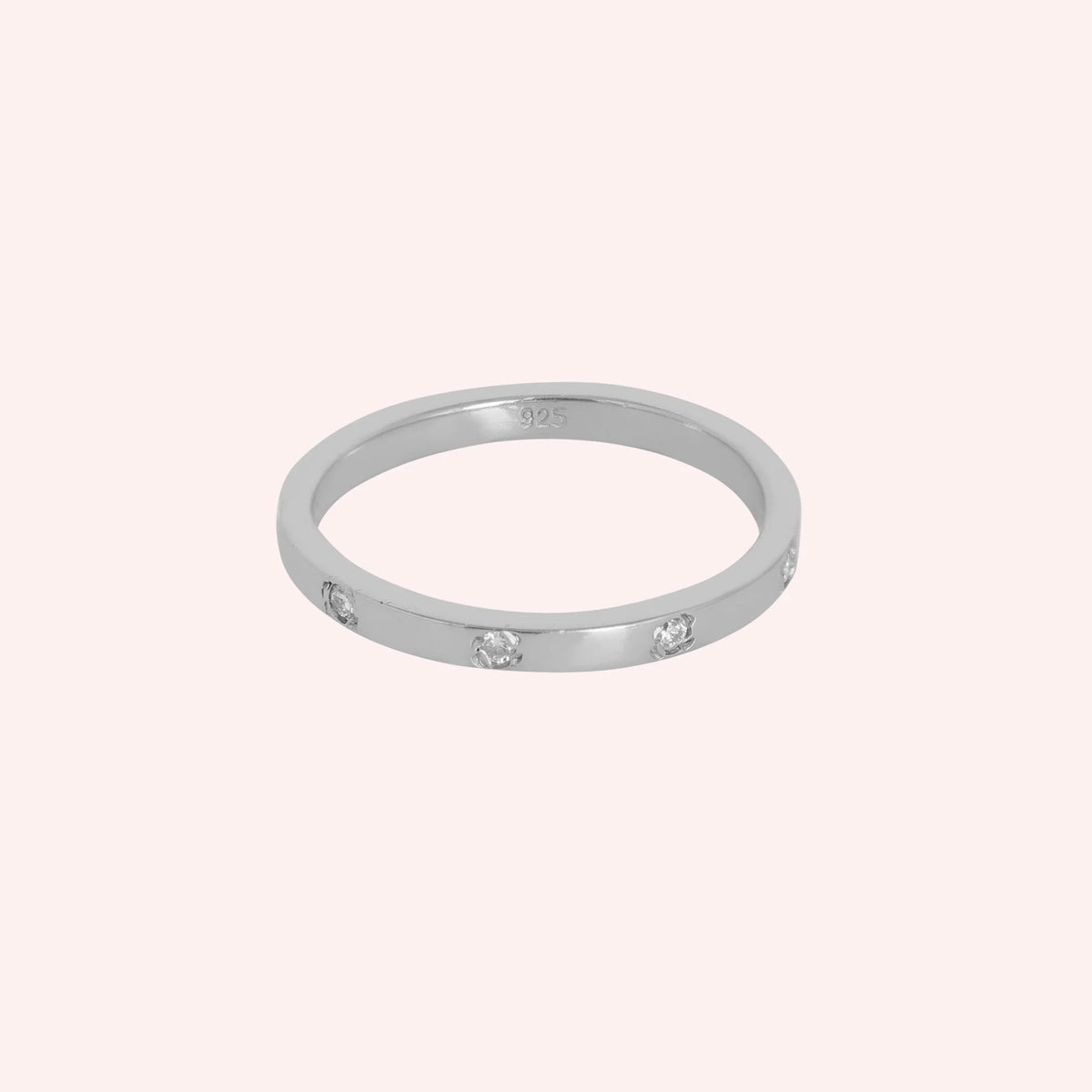 Stacking_ring_in_sterling_silver_with_a_round_CZ_stones_at_front_angle_view_on_solid_pink_background