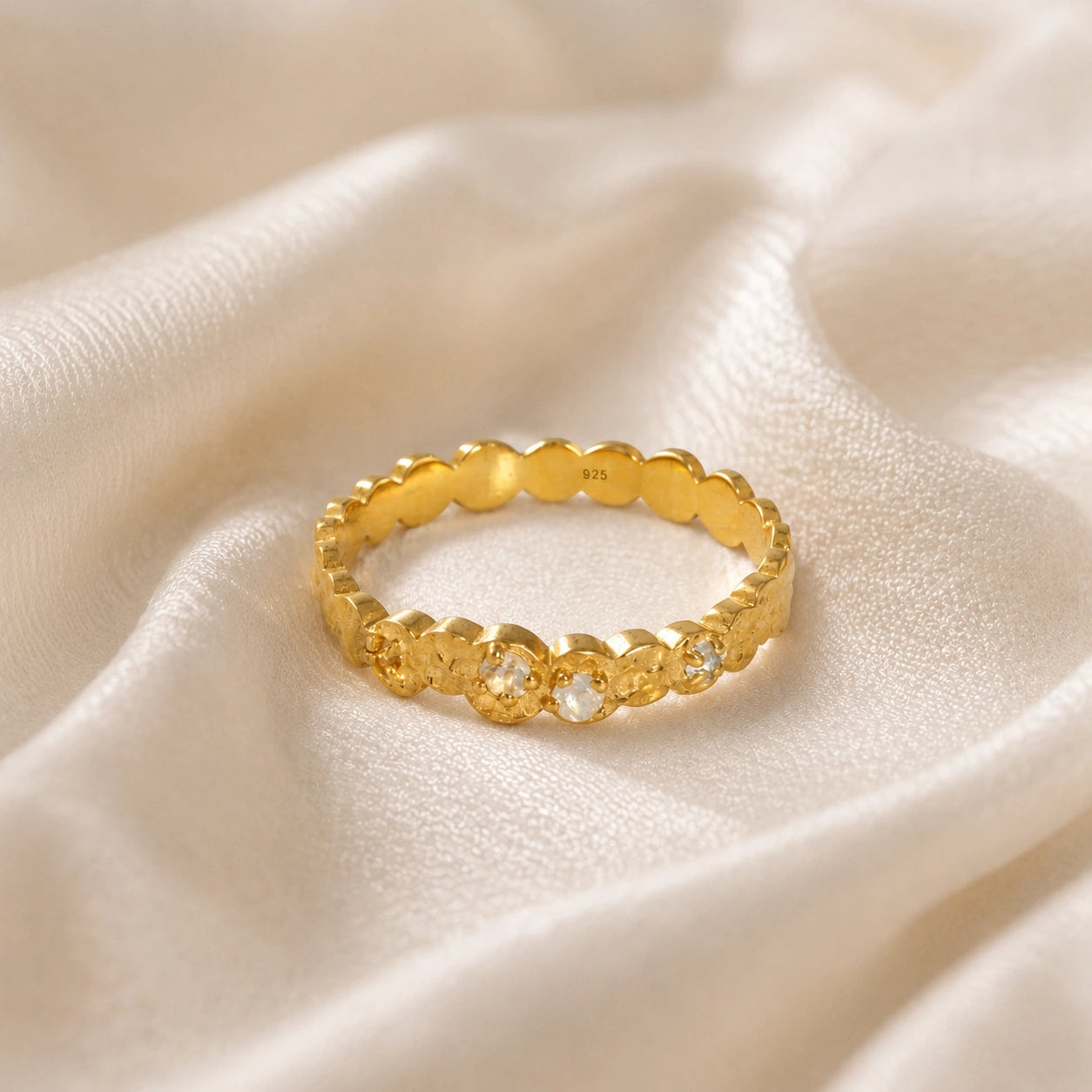 Stacking_ring_in_gold_plated_silver_textured_band_with_moonstones_in_front_angled_view_on_soft_fabric_background