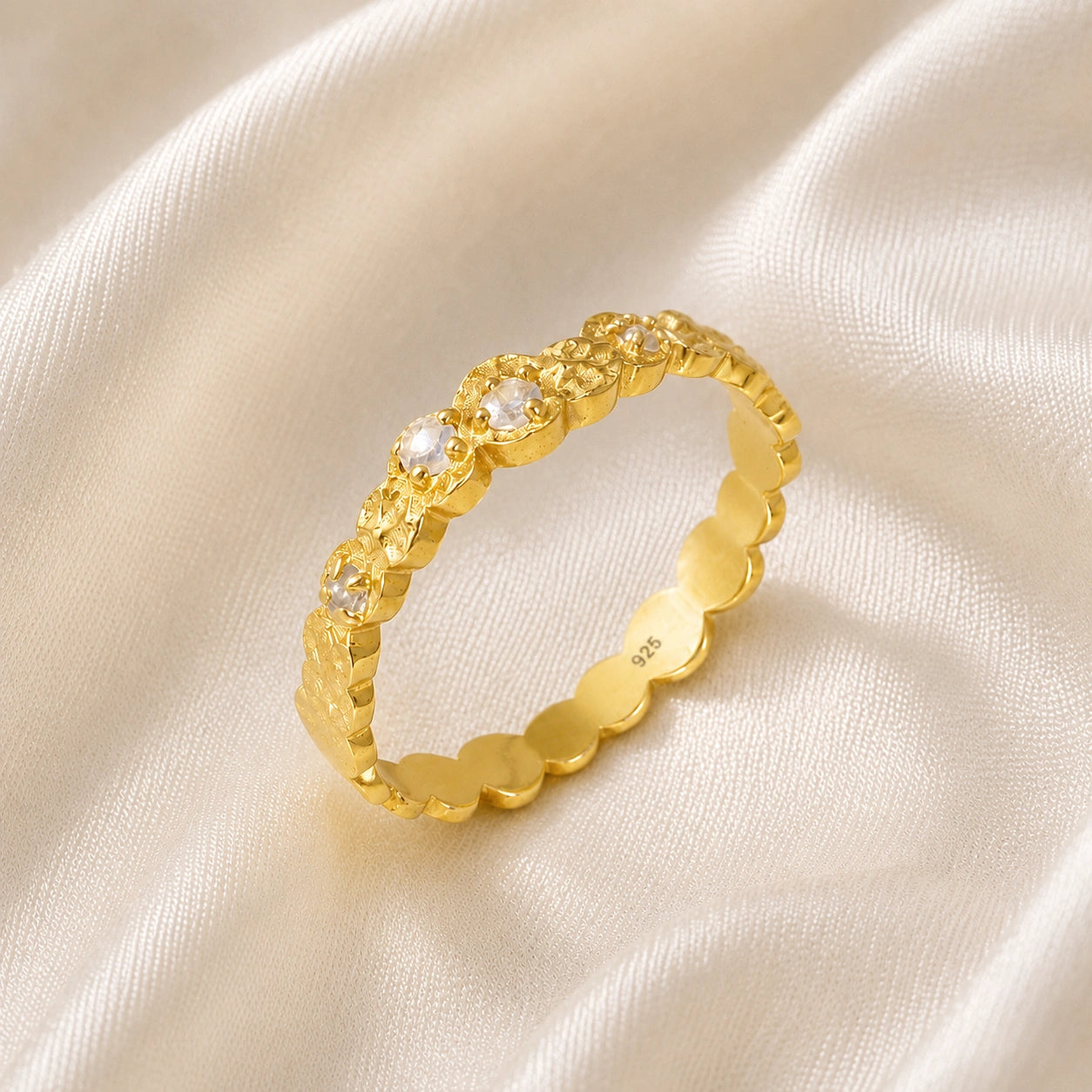 Stacking_ring_in_gold_plated_silver_textured_band_with_moonstones_in_angled_view_on_soft_fabric_background