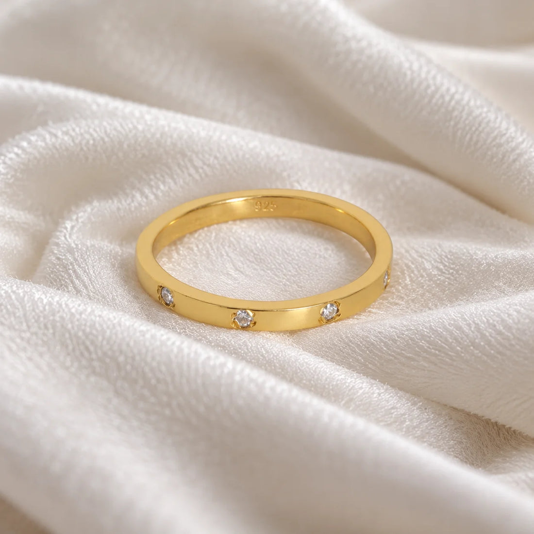 Stacking_ring_in_gold_plated_silver_with_a_round_CZ_stones_at_front_angle_view_on_soft_fabric_background