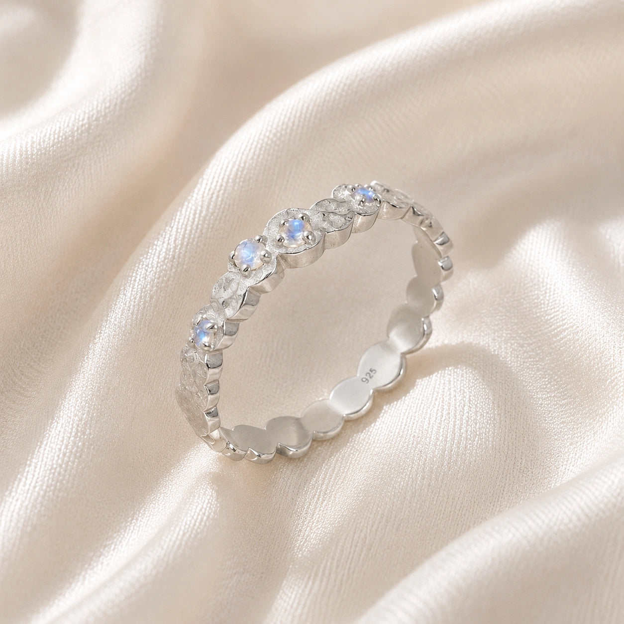 Stacking_ring_in_sterling_silver_textured_band_with_moonstones_in_angled_view_on_soft_fabric_background