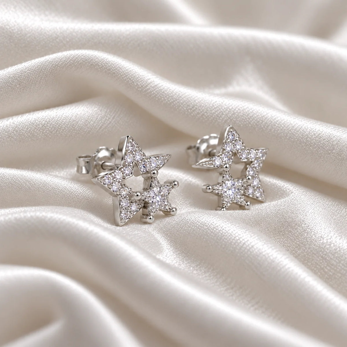 Star_earrings_in_sterling_silver_with_CZ_stones_at_side_angle_view_on_soft_fabric_background