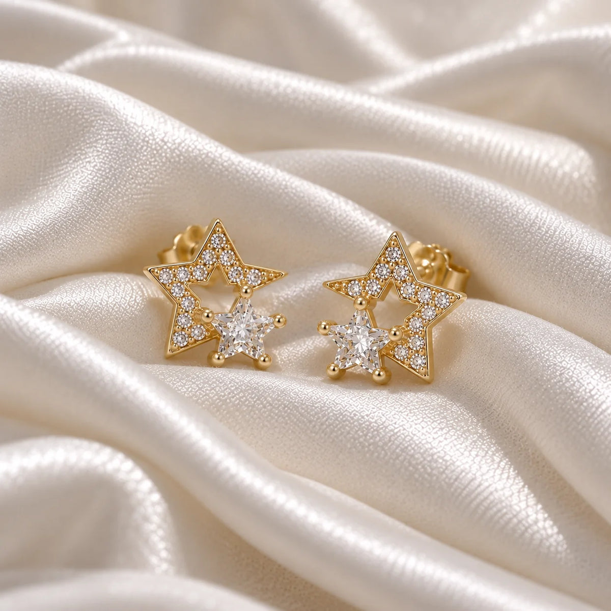 Star_earrings_in_gold_plated_silver_with_CZ_stones_at_front_angle_view_on_soft_fabric_background