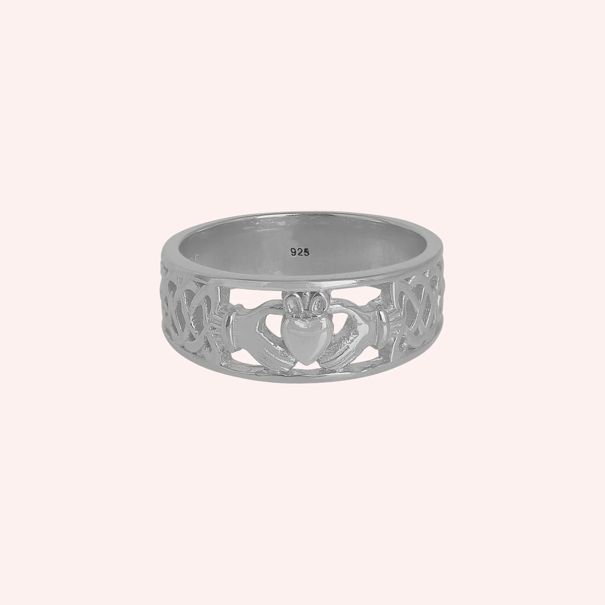 Statement_ring_in_sterling_silver_with_claddagh_design_band_at_front_angle_view_on_solid_pink_background