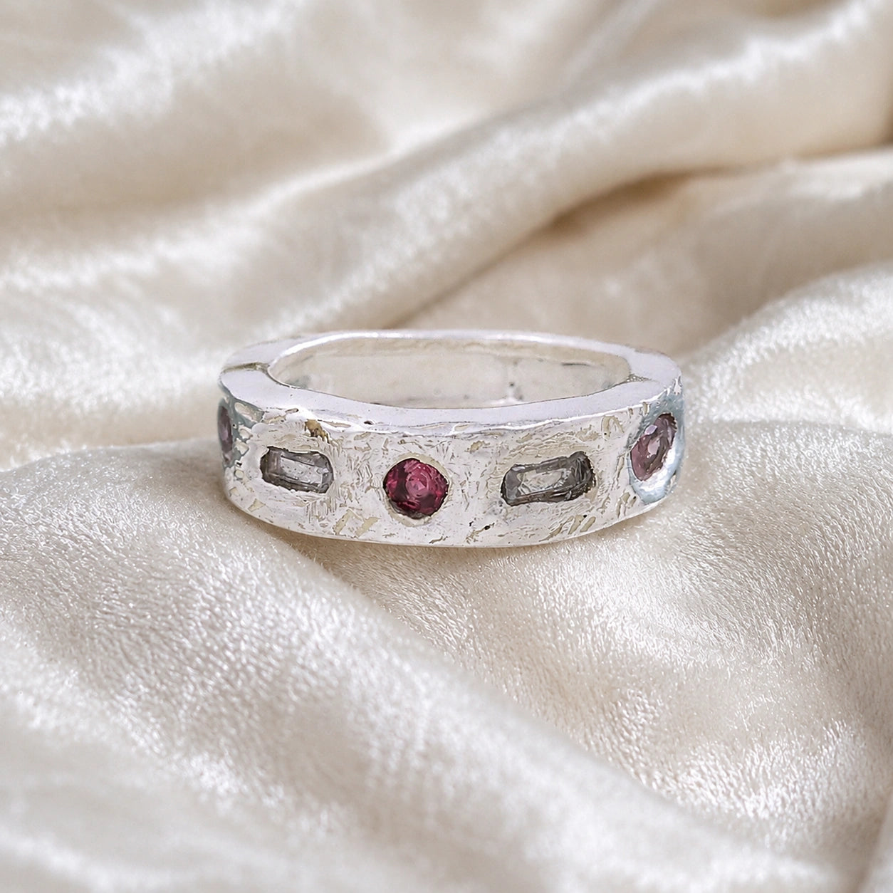 Statement_ring_in_sterling_silver_at_front_angle_with_multi_stones_on_a_soft_fabric_background