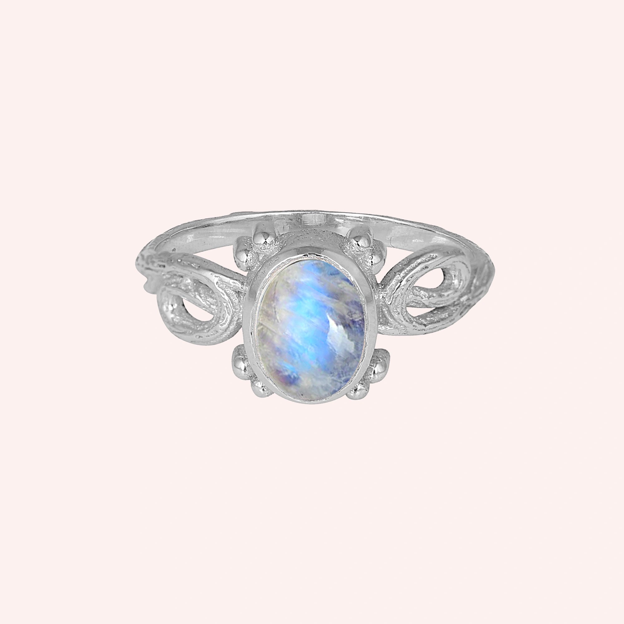 Statement_ring_sterling_silver_with_oval_moonstone_and_intricate_band_detail_front_angle_view_on_solid_pink_background