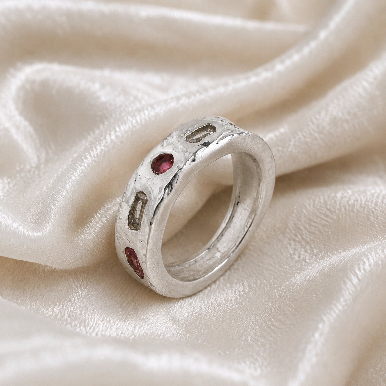 Statement_ring_in_sterling_silver_at_slightly_angled_view_with_multi_stones_on_a_soft_fabric_background