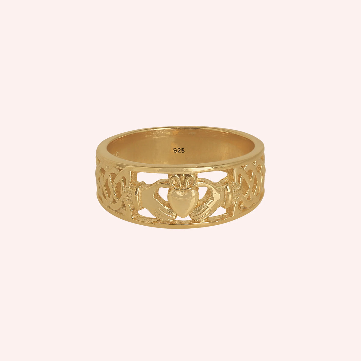 Statement_ring_in_gold_plated_silver_with_claddagh_design_band_at_front_angle_view_on_solid_pink_background