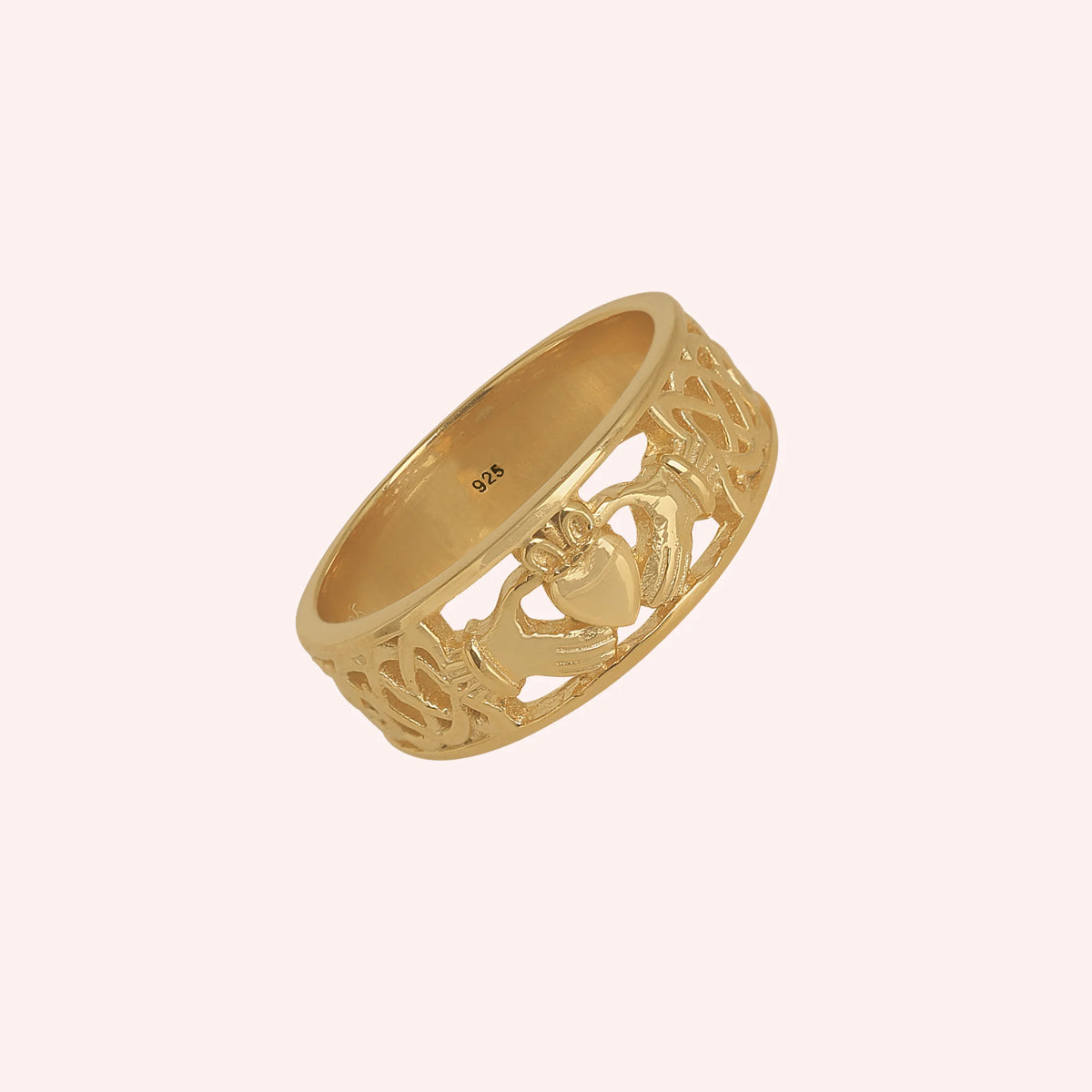 Statement_ring_in_gold_plated_silver_with_claddagh_design_band_at_side_angle_view_on_solid_pink_background