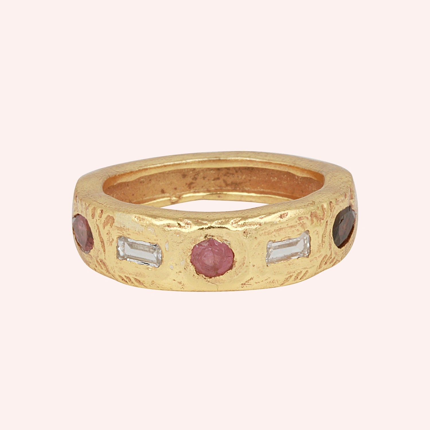 Statement_ring_in_gold_plated_silver_at_front_angle_with_multi_stones_on_a_solid_pink_background