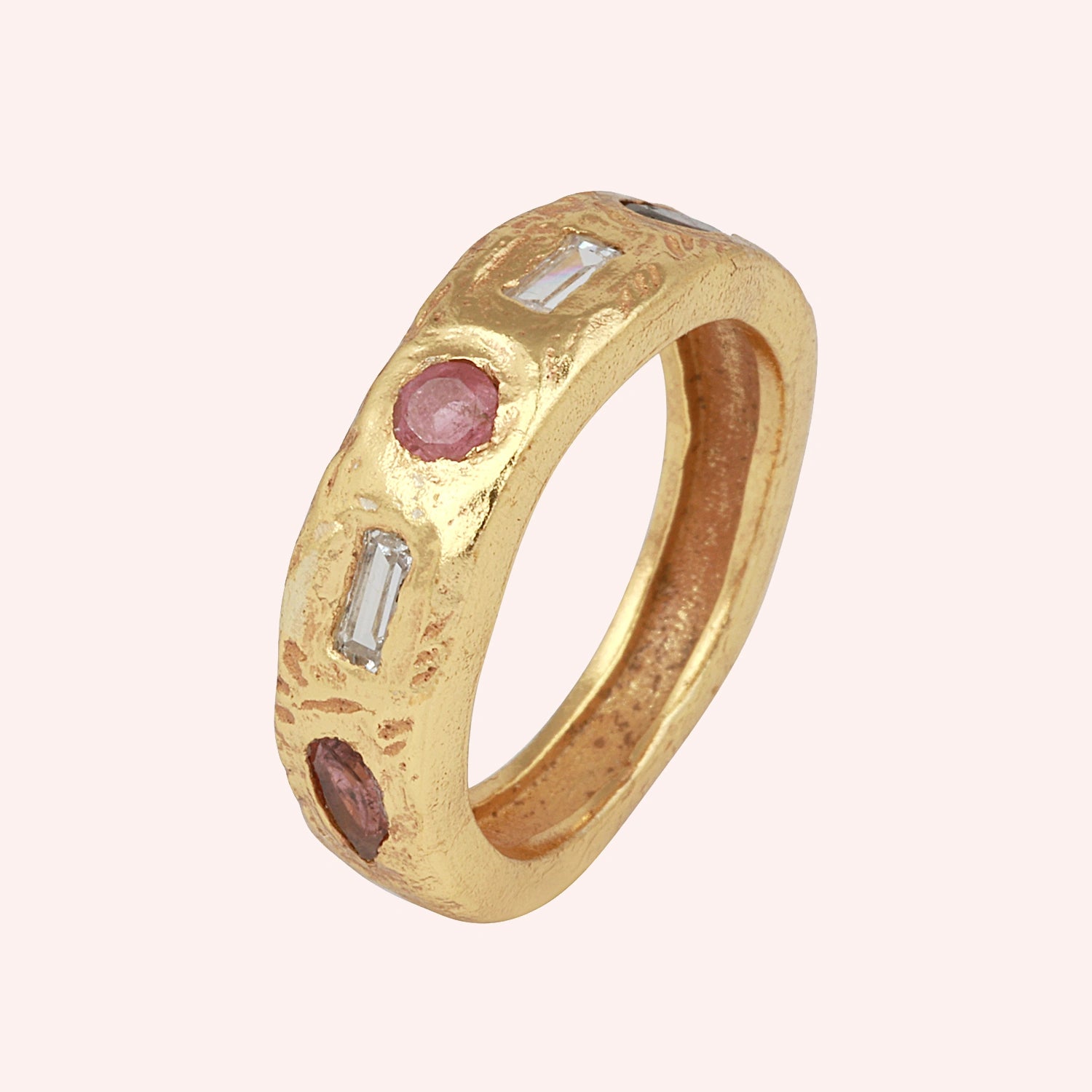 Statement_ring_in_gold_plated_silver_at_slight_angle_with_multi_stones_on_a_solid_pink_background