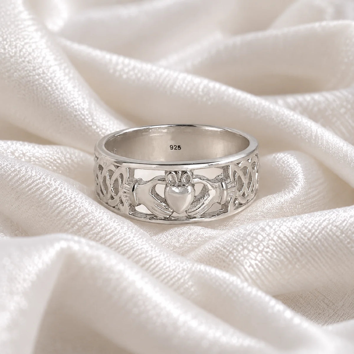 Statement_ring_in_sterling_silver_with_claddagh_design_band_at_front_angle_view_on_soft_fabric_background