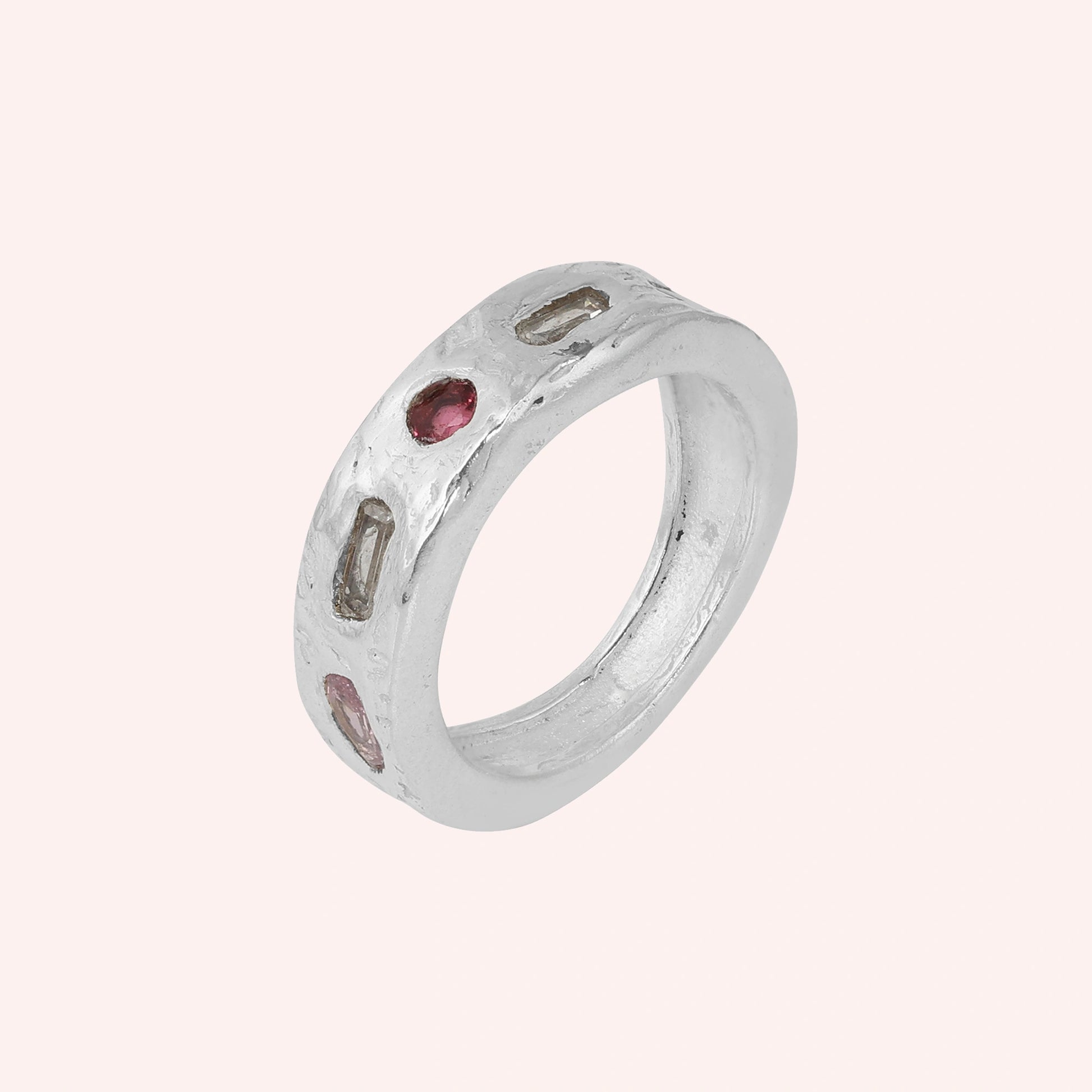 Statement_ring_in_sterling_silver_at_slight_angle_with_multi_stones_on_a_solid_pink_background