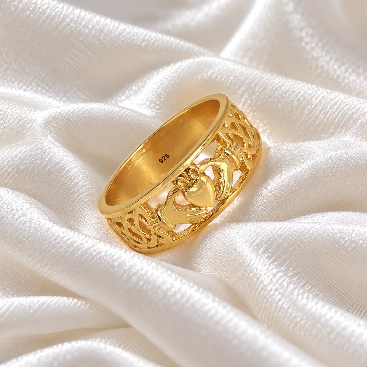 Statement_ring_in_gold_plated_silver_with_claddagh_design_band_at_side_angle_view_on_soft_fabric_background