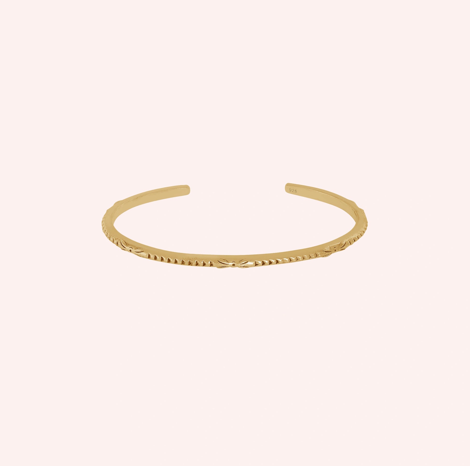 Sterling_silver_bracelet_in_gold_plated_silver_with_engraved_design_at_front_angle_view_on_solid_pink_background
