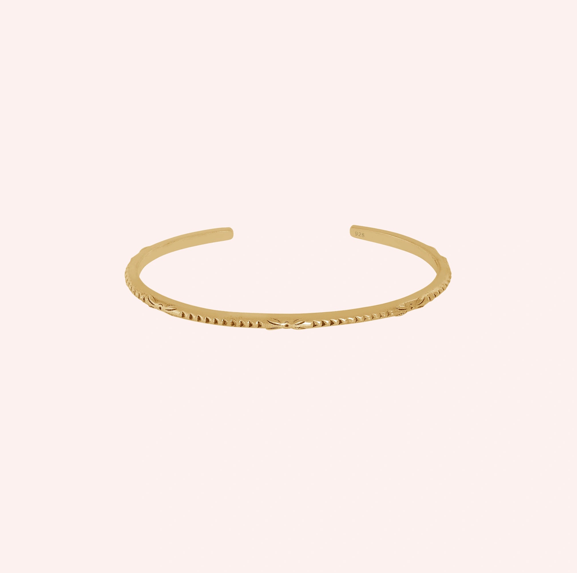Sterling_silver_bracelet_in_gold_plated_silver_with_engraved_design_at_front_angle_view_on_solid_pink_background