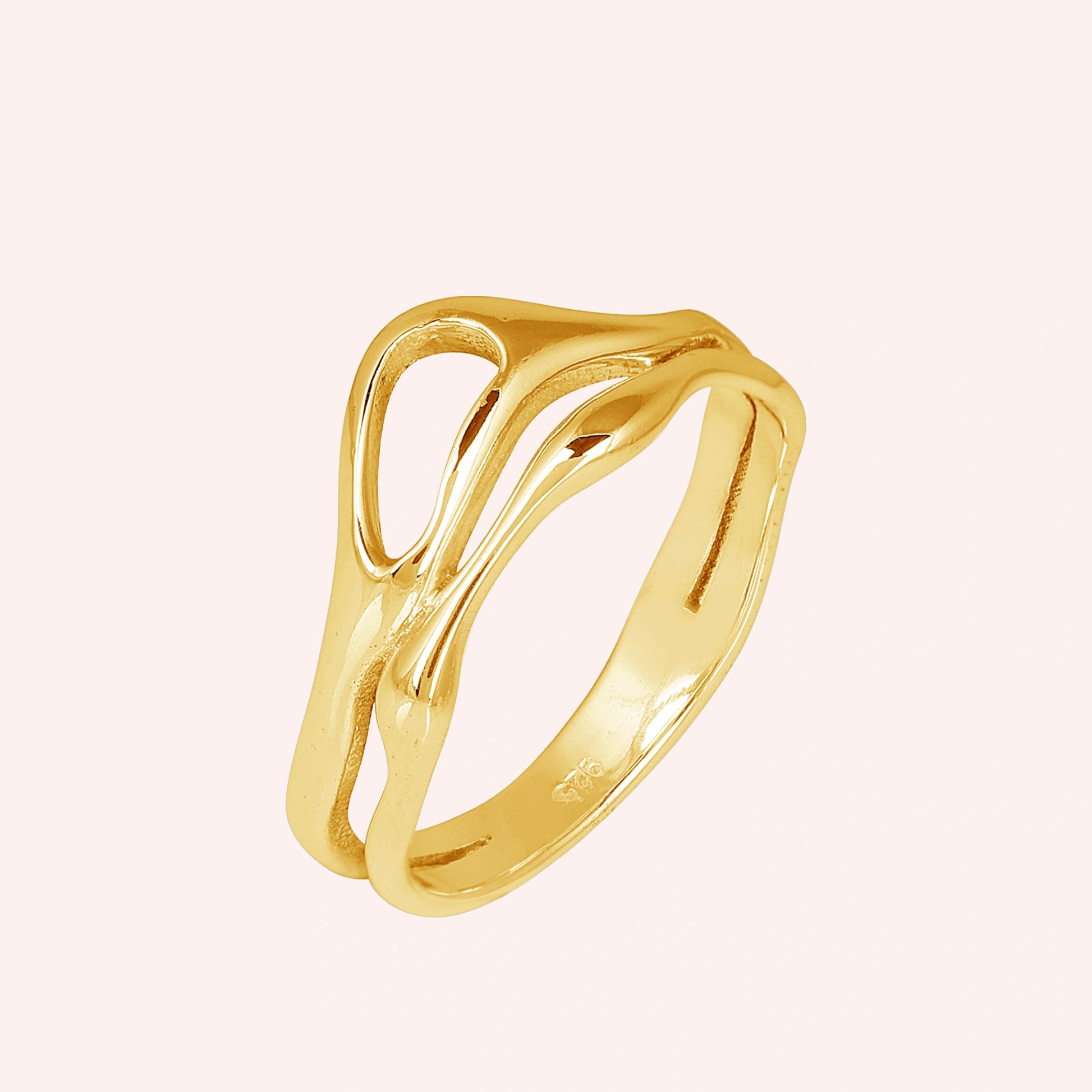 A gold plated wave band ring on a pink background shown from a side angle as a polished sterling silver rings for women