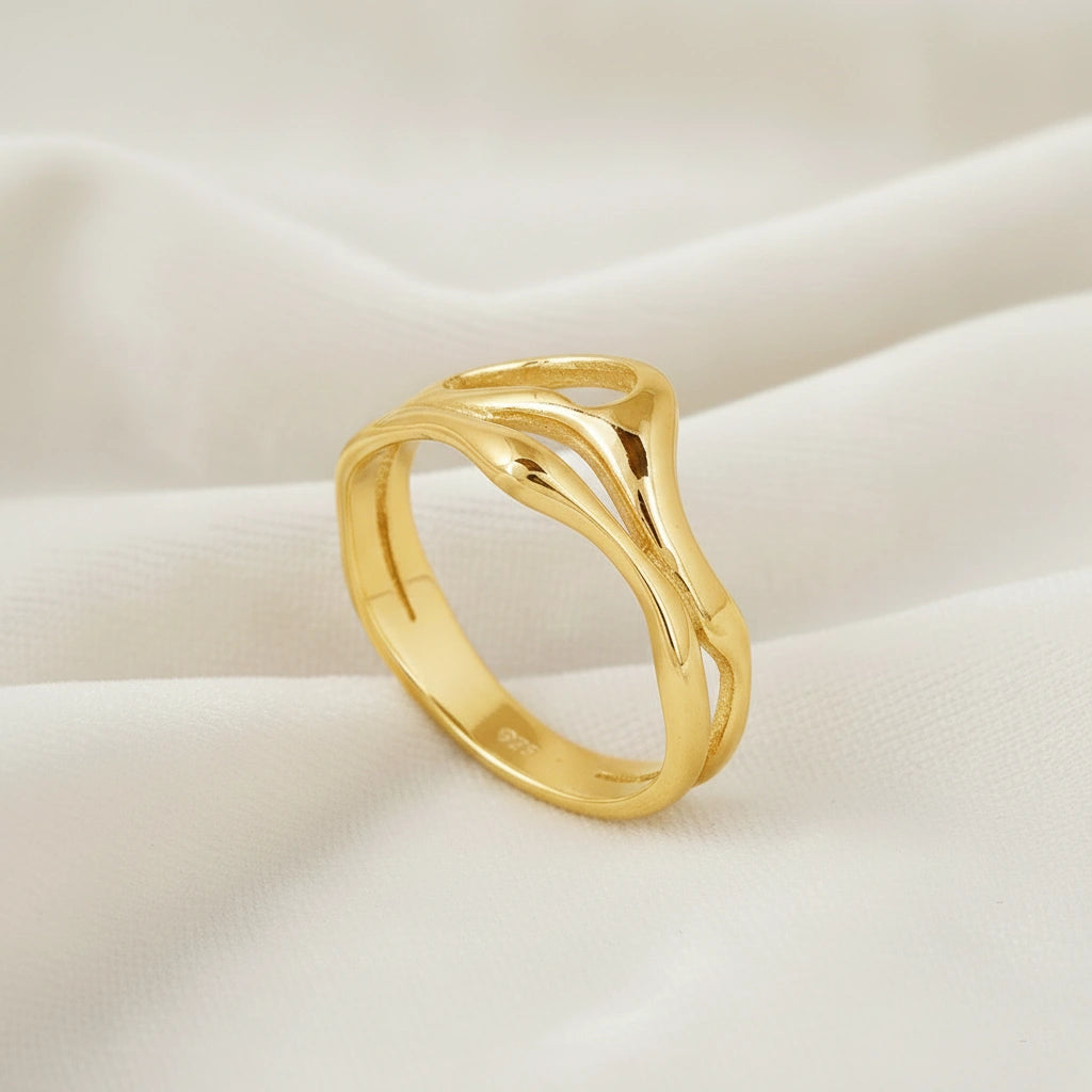 A gold plated wave band ring on white velvet shown from a side angle as a polished sterling silver rings for women accessory